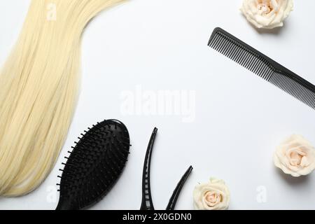 Composition de pose plate avec différents outils de coiffeur et fleurs sur fond blanc, espace pour le texte Banque D'Images