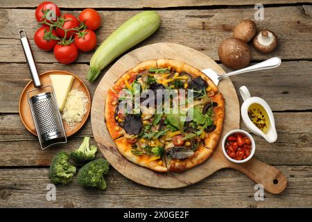 Délicieuse pizza végétarienne et ingrédients sur table en bois, plat Banque D'Images