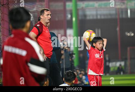 Tianjin, Chine. 11 avril 2024. L’entraîneur serbe Mirko Radovanovic (2e l) regarde lors d’une séance d’entraînement pour jeunes joueurs de football au Centre d’entraînement des jeunes de l’Association de football de Tianjin dans la municipalité de Tianjin, dans le nord de la Chine, le 11 avril 2024. La Tianjin Football Association a invité les entraîneurs de football étrangers à améliorer les compétences et la condition physique des jeunes footballeurs chinois locaux. Crédit : Sun Fanyue/Xinhua/Alamy Live News Banque D'Images