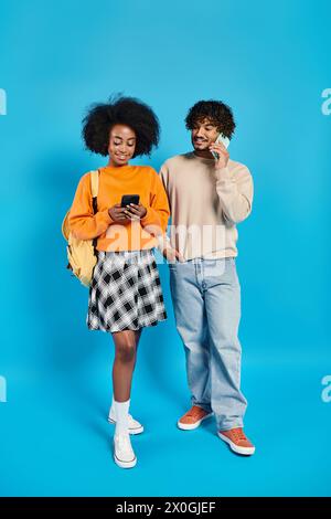 Couple d'étudiants interraciaux en tenue décontractée debout à côté de l'autre sur fond bleu dans le studio. Banque D'Images