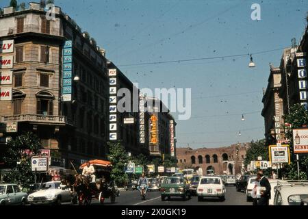 Une calèche et des voitures sur la rue via Vittorio Veneto à Rome en face de rangées de maisons avec des panneaux publicitaires. [traduction automatique] Banque D'Images