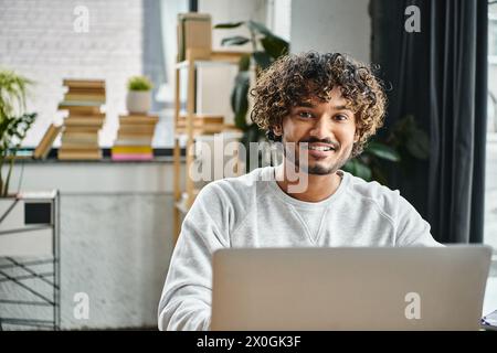 Un homme aux origines diverses est assis dans son ordinateur portable, explorant le monde numérique de l'information et des possibilités. Banque D'Images
