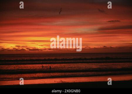 Deux bains sur la plage de Kuta à la lumière du coucher du soleil. [traduction automatique] Banque D'Images