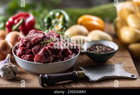 Morceaux de bœuf hachés dans un bol avec des légumes, prêts pour le goulash. Banque D'Images