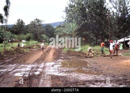 'Les gens sur un chemin boueux et de terre dans le village de MTO wa Mbu (''rivière Mosquito'') au lac Manyara en Tanzanie. [traduction automatique]' Banque D'Images