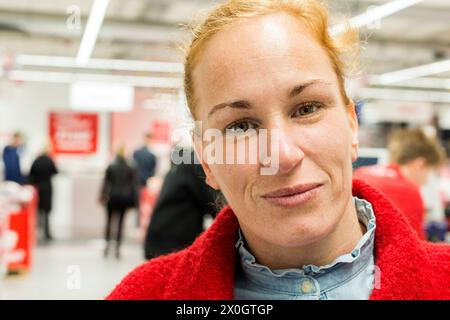 Portrait femme à l'intérieur du magasin. Jeune femme adulte aux cheveux rouges visitant un magasin d'électronique grand public pour acheter un appareil photo. mais noet sait-il comment. Tilburg, pays-Bas. MRYES Tilburg Media Markt, Pieter Vreedeplein Noord-Brabant Nederland Copyright : xGuidoxKoppesxPhotox Banque D'Images