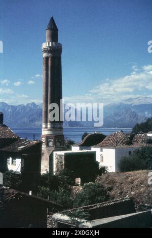 Le minaret de la Mosquée Yivli Minare à Antalya avec les montagnes à la mer Méditerranée en arrière-plan. [traduction automatique] Banque D'Images