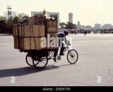 Un homme sur un vélo à trois roues transporte des caisses à Pékin. Banque D'Images