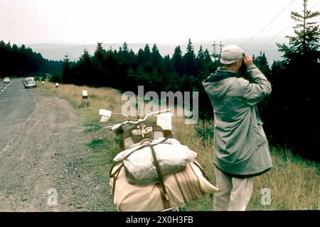 Un homme avec des jumelles et une Lambretta sur le bord de la route. Banque D'Images