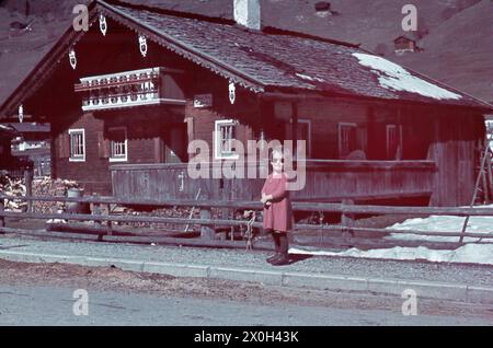 Une petite fille dans une robe en maille lunettes de soleil est debout devant une maison de campagne dans la municipalité Gerlos au Tyrol / Autriche. Banque D'Images