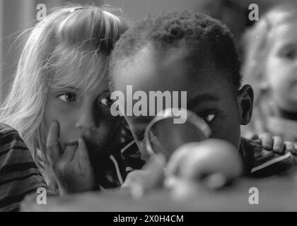 Le garçon examine les escargots avec une loupe tandis que la fille le regarde attentivement [traduction automatique] Banque D'Images