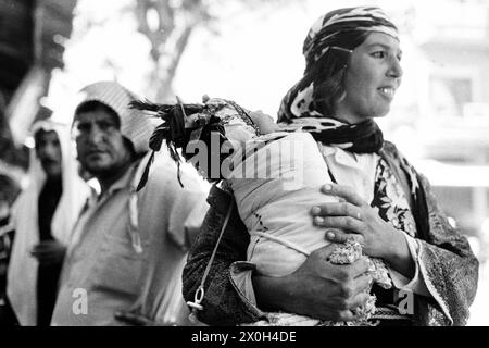 Une mère porte son bébé traditionnellement emmailloté. [traduction automatique] Banque D'Images