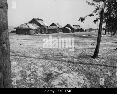 Un hameau avec des maisons en bois de chaume se trouve abandonné dans l'étendue hivernale. La photo a été prise par un membre du Radfahrgrenadierregiment 2 / Radfahrsicherungsregiment 2, dans la partie nord du front est. [traduction automatique] Banque D'Images