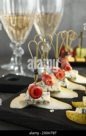 Canapés savoureux avec poires, fromage bleu et prosciutto sur table, gros plan Banque D'Images