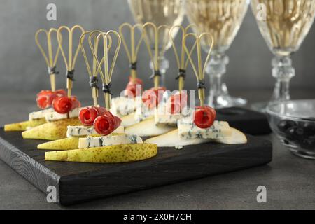 Canapés savoureux avec poires, fromage bleu et prosciutto sur table grise, gros plan Banque D'Images
