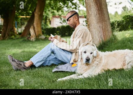 Un Afro-américain handicapé est assis dans l'herbe avec son chien Labrador, incarnant la diversité et l'inclusion. Banque D'Images