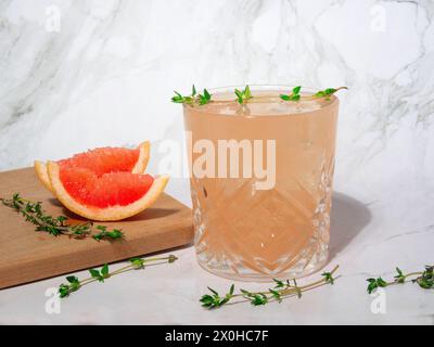 Mocktail rafraîchissant de pamplemousse avec de la glace et du thym sur un fond gris. Banque D'Images