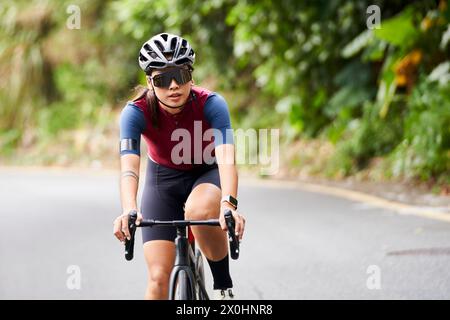 jeune femme asiatique cycliste cycliste cycliste à l'extérieur sur la route rurale Banque D'Images