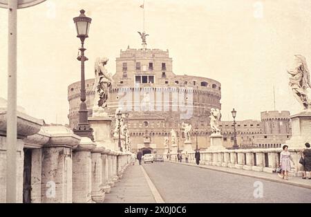 Castel Sant'Angelo depuis le pont Castel Sant'Angelo. Les voitures roulent sur le pont. Les passants marchent sur les trottoirs. A droite et à gauche se trouvent les statues des anges. [traduction automatique] Banque D'Images