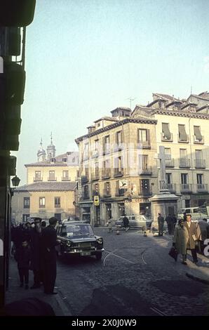 Place animée à l'intersection avec Calle de Cuchilleros. Un monument avec une croix sur la droite. Les piétons marchent sur les trottoirs, les voitures roulent dans la rue. Des maisons avec des magasins bordent la rue. [traduction automatique] Banque D'Images