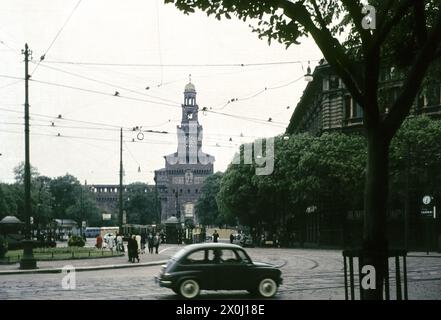 Vue sur une place avec bus et personnes. À l'arrière la Torre Filarete, la zone d'entrée du Castello Sforzesco [traduction automatique] Banque D'Images