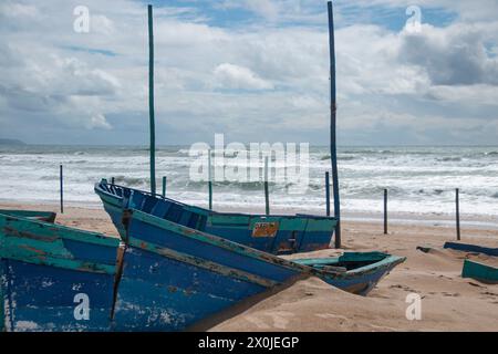 Bateaux en bois bloqués sur la plage abandonnés et décrépis en raison du mauvais temps avec une mer agitée en arrière-plan Banque D'Images