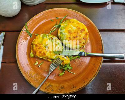 Moitiés de petit pain garnies de fromage, d'avocat et de salade de roquette dans une assiette Banque D'Images