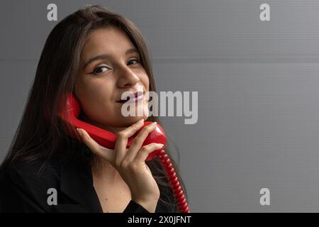 Jeune femme latino-américaine avec un casque rouge et une attitude positive, posant à la caméra. Concept de technologie jeune et vintage Banque D'Images