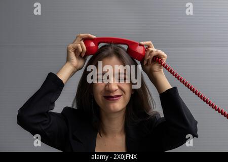 Jeune femme latino-américaine avec un casque rouge et une attitude positive, pose avec des gestes amusants. Concept de technologie jeune et vintage Banque D'Images