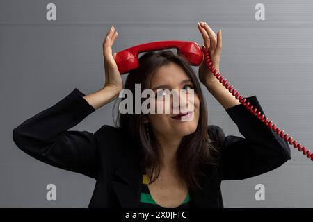 Jeune femme latino-américaine avec un casque rouge et une attitude positive, pose avec des gestes amusants. Concept de technologie jeune et vintage Banque D'Images