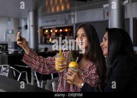 Maman et sa fille latino-américaine discutent et partagent une boisson aux fruits tout en prenant une photo. Fête des mères et concepts de vie saine Banque D'Images