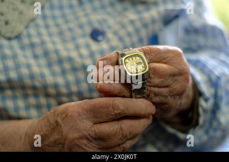 Grand-mère tenant une vieille montre dans ses mains. Concept de vieillesse, passage du temps et solitude Banque D'Images