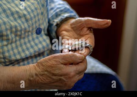 Grand-mère tenant une vieille montre dans ses mains. Concept de vieillesse, passage du temps et solitude Banque D'Images