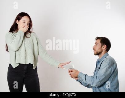 Homme à genoux proposant le mariage à sa petite amie avec une boîte à anneaux dans ses mains et elle le rejette Banque D'Images