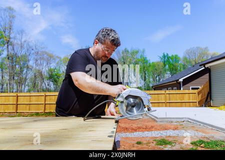 À l'aide d'une scie à main, le menuisier garnit les panneaux de contreplaqué Banque D'Images