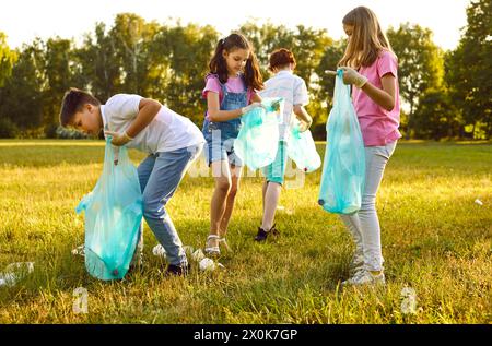 Groupe d'enfants avec des sacs poubelle collectant les ordures en plastique dans le parc d'été à l'extérieur. Banque D'Images