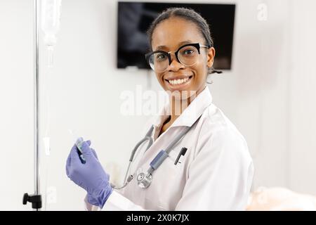 Une femme médecin portant un manteau blanc et des gants bleus, prête à aider les patients dans un cadre médical. Banque D'Images