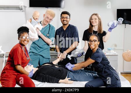 Un groupe diversifié de professionnels de la santé, y compris des médecins et des infirmières, debout ensemble et souriant pour une photo de groupe dans un cadre hospitalier. Banque D'Images