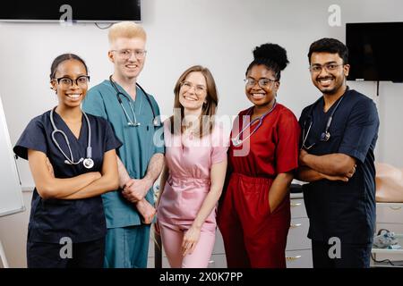 Un groupe de médecins en tenue professionnelle debout étroitement ensemble, regardant vers la caméra avec des expressions sérieuses, discutant peut-être médical Banque D'Images