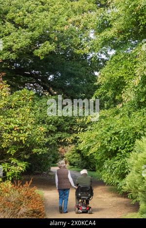 Angleterre, East Sussex, Sheffield Park and Gardens, Man on Mobility Scooter et épouse sur Foothpath Banque D'Images