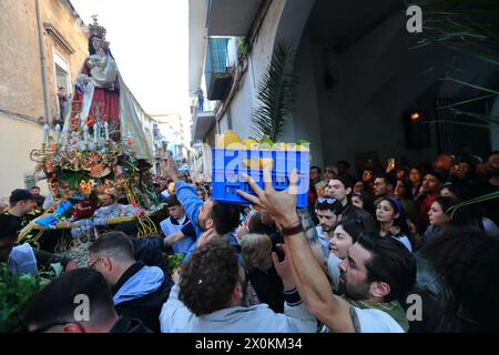 La statue de la Madonna delle Galline est portée en procession à travers les rues et est accueillie par les fidèles avec des fleurs, des offrandes de nourriture. Banque D'Images