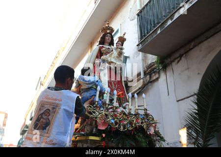 La statue de la Madonna delle Galline est portée en procession à travers les rues et est accueillie par les fidèles avec des fleurs, des offrandes de nourriture. Banque D'Images