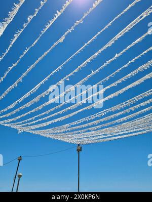 Une guirlande blanche est suspendue décorée de façon festive au-dessus d'une place publique à Cala Ratjada, décoration festive pour une fête, vacances d'été à Majorque, Espagne Banque D'Images