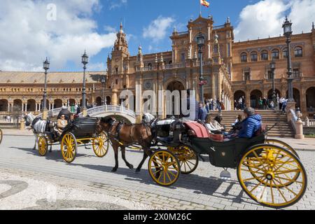 Séville, Espagne - 3 mars 2024 : calèches transportant des touristes à travers la Plaza de España, à Séville Banque D'Images