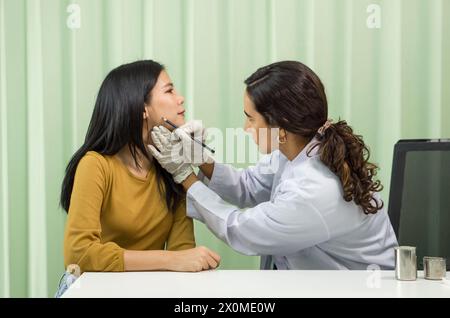 Un professionnel de la santé effectue précisément une procédure de diagnostic du menton sur une patiente dans un environnement clinique désinfecté. Ils ont Banque D'Images