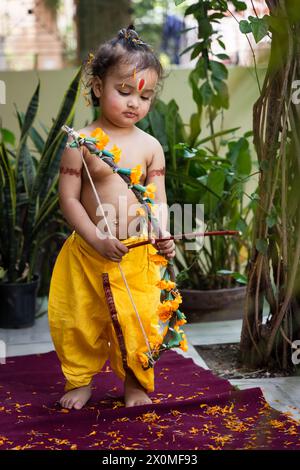 Portrait de mignon garçon indien robes comme seigneur rama avec arc à l'extérieur avec fond flou le jour Banque D'Images