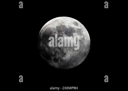 Une photographie en noir et blanc montrant la pleine lune dans le ciel de minuit, sur fond noir foncé. L'objet astronomique brille brillamment, c Banque D'Images