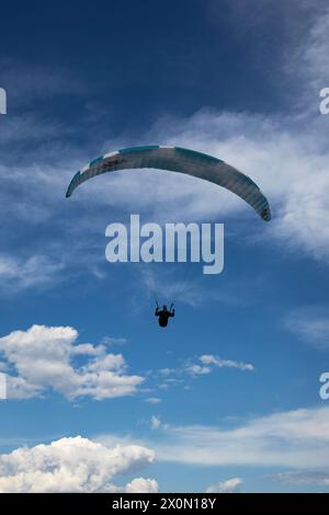 Parapente vole dans le ciel bleu sur fond de nuages Banque D'Images