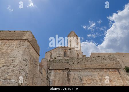 Une vue vers le haut du château d'Eivissa Almudaina à Ibiza, mettant en valeur ses murs de pierre historiques et sa tour de l'horloge robuste sur fond de cl dispersé Banque D'Images