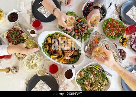 Table pleine de nourriture délicieuse dans des assiettes, vue de dessus. Poulet cuit au four avec pommes de terre, caviar en tartelettes, salades, collations diverses et boissons lors d'un dîner de gala Banque D'Images
